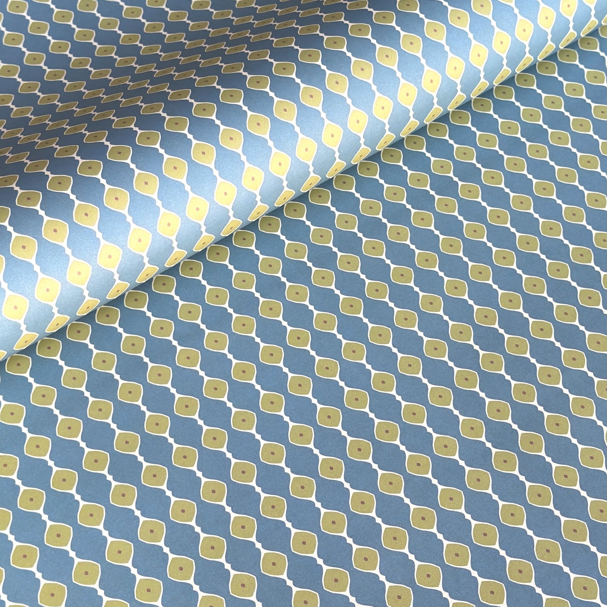 wrapping paper with a geometric pattern of lines of little lime green diamonds on a teal