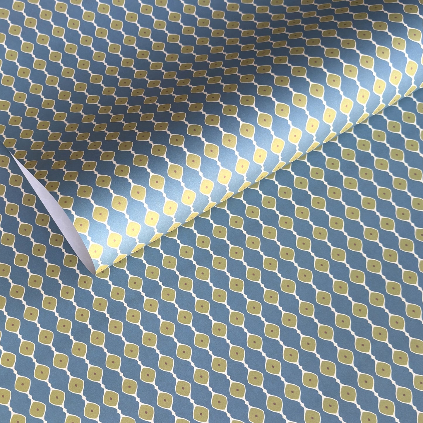 wrapping paper with a geometric pattern of lines of little lime green diamonds on a teal