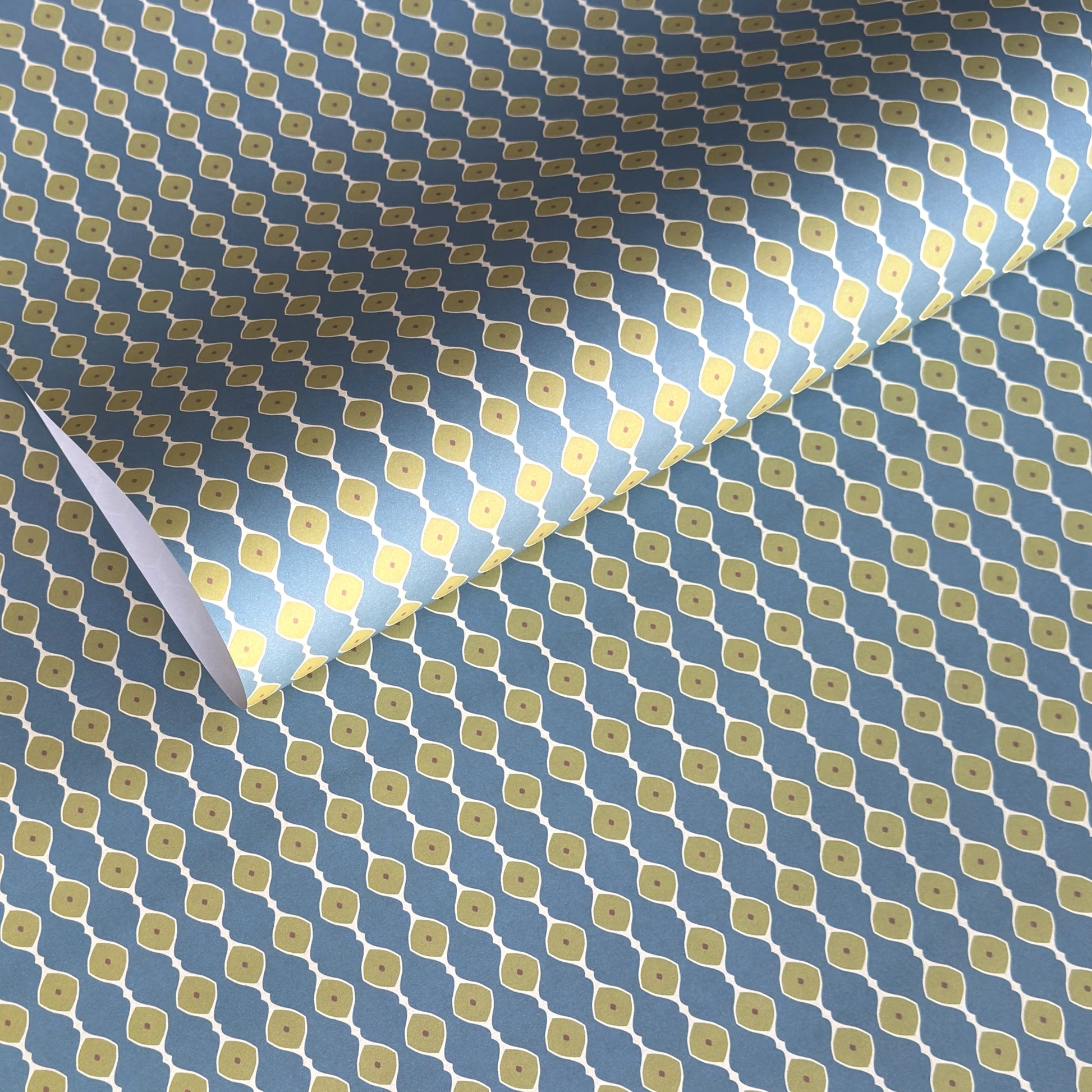 wrapping paper with a geometric pattern of lines of little lime green diamonds on a teal