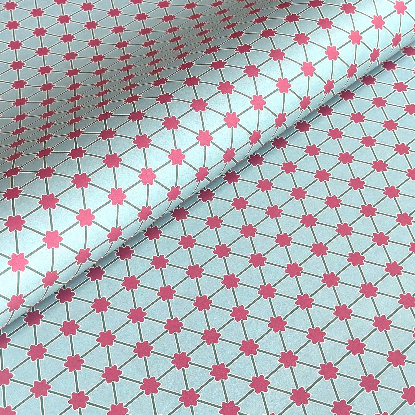 Patterned paper with pink floral shapes on a light blue background