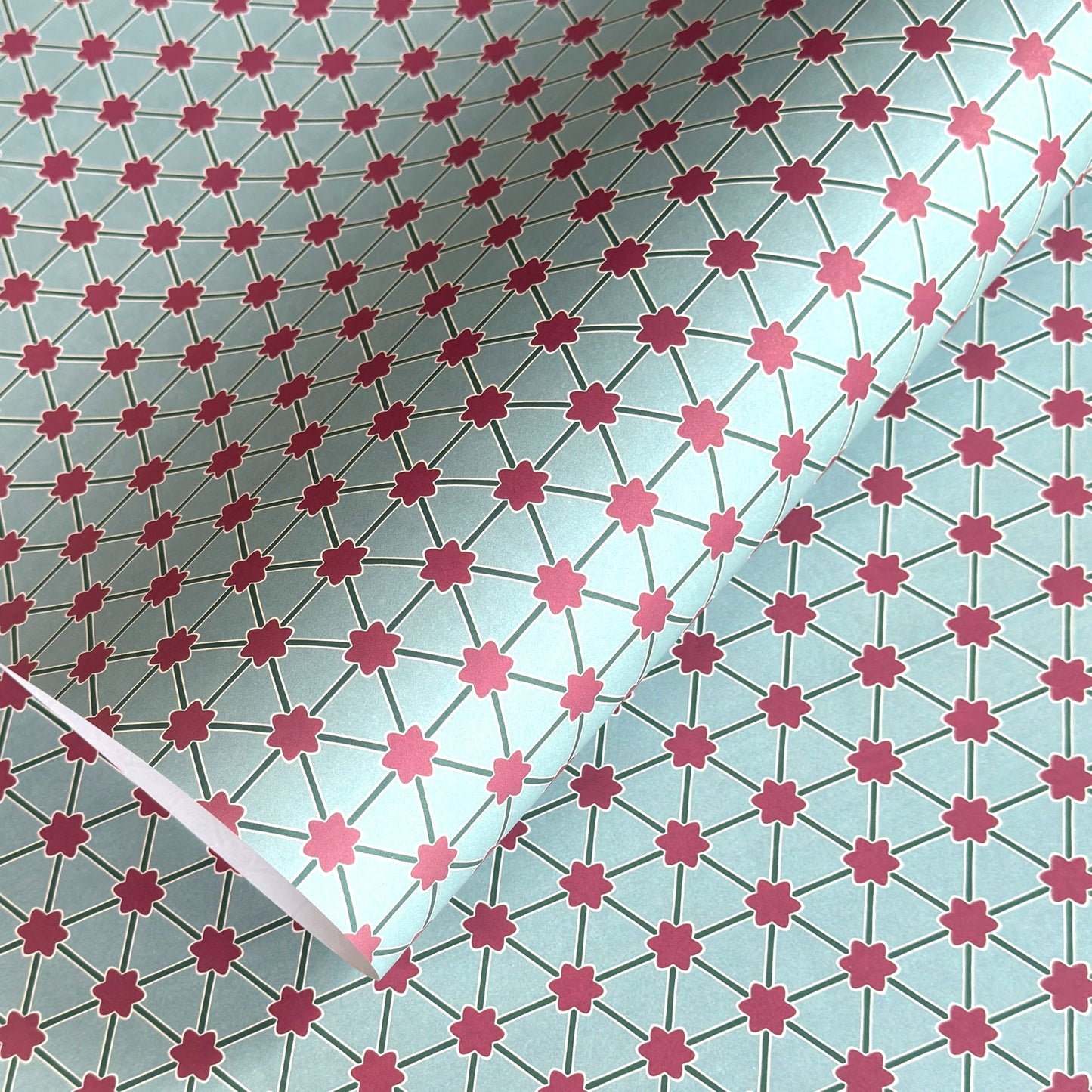 Patterned paper with pink floral shapes on a light blue background
