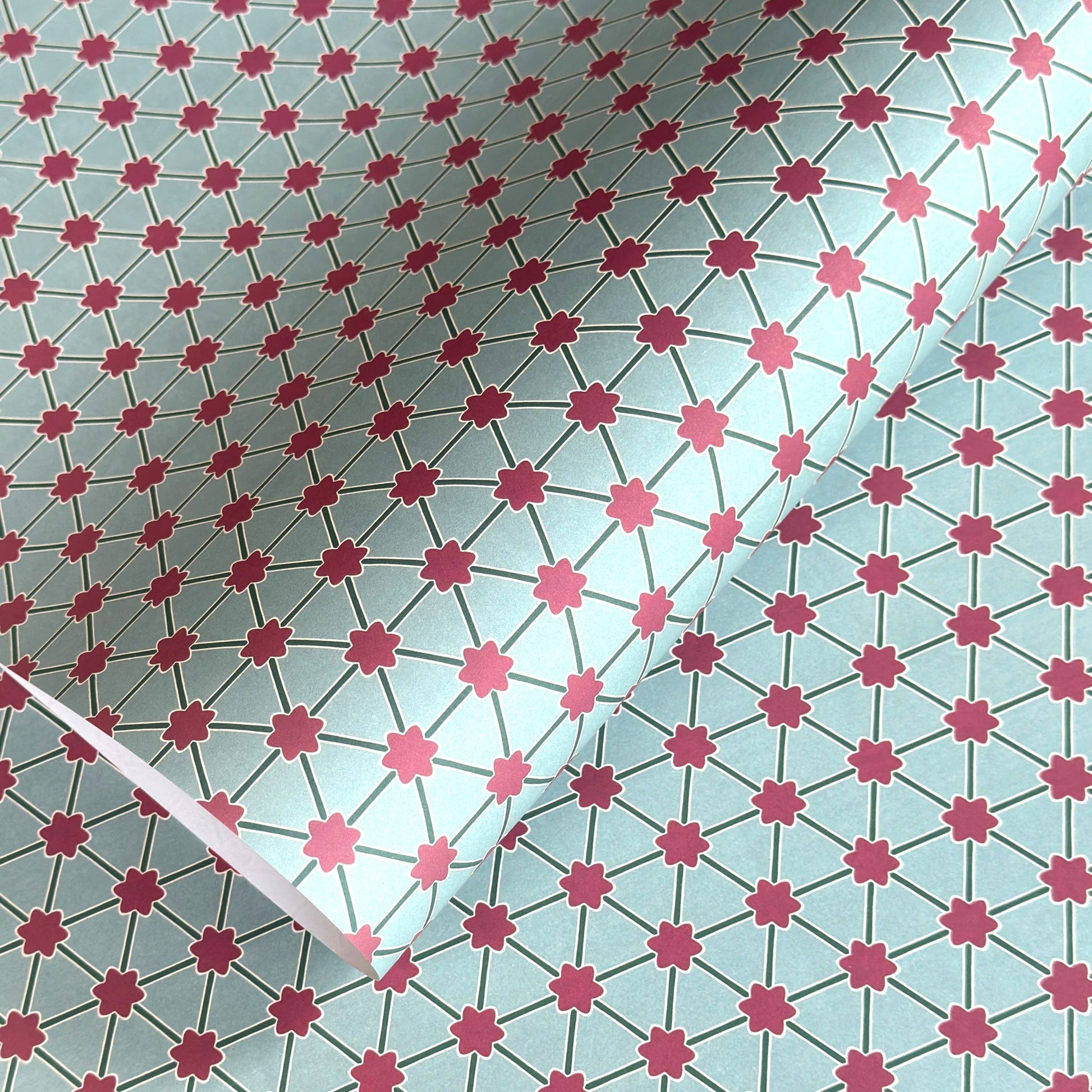 Patterned paper with pink floral shapes on a light blue background