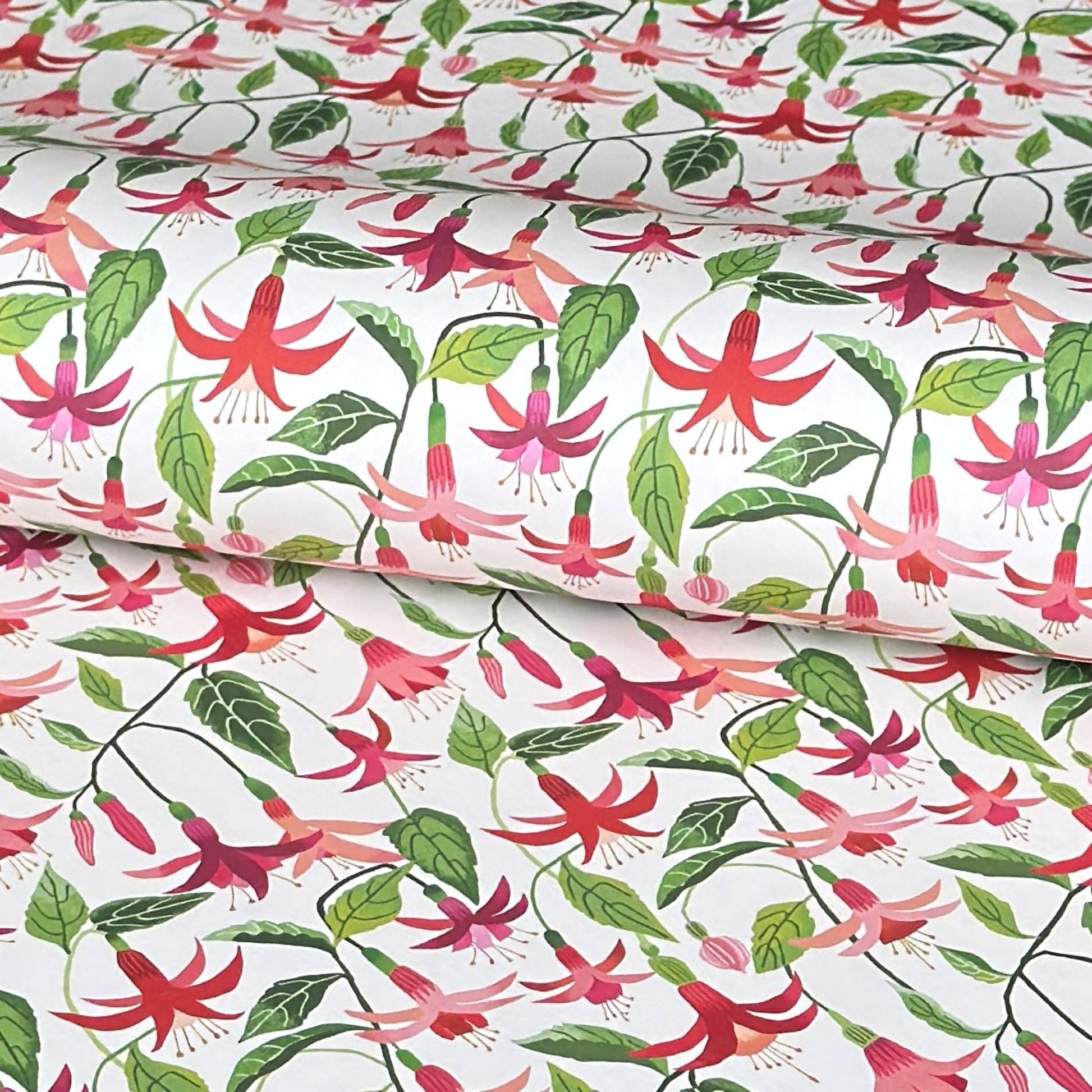 a sheet of wrapping paper with stylised pink fuchsia flowers, green leaves on a white background