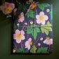 a sheet of wrapping paper with a dark indigo background and pink japanese anemone flowers and green foliage