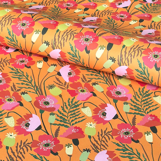 a sheet of wrapping paper with a pattern of stylised pink poppies with green foliage on an orange background