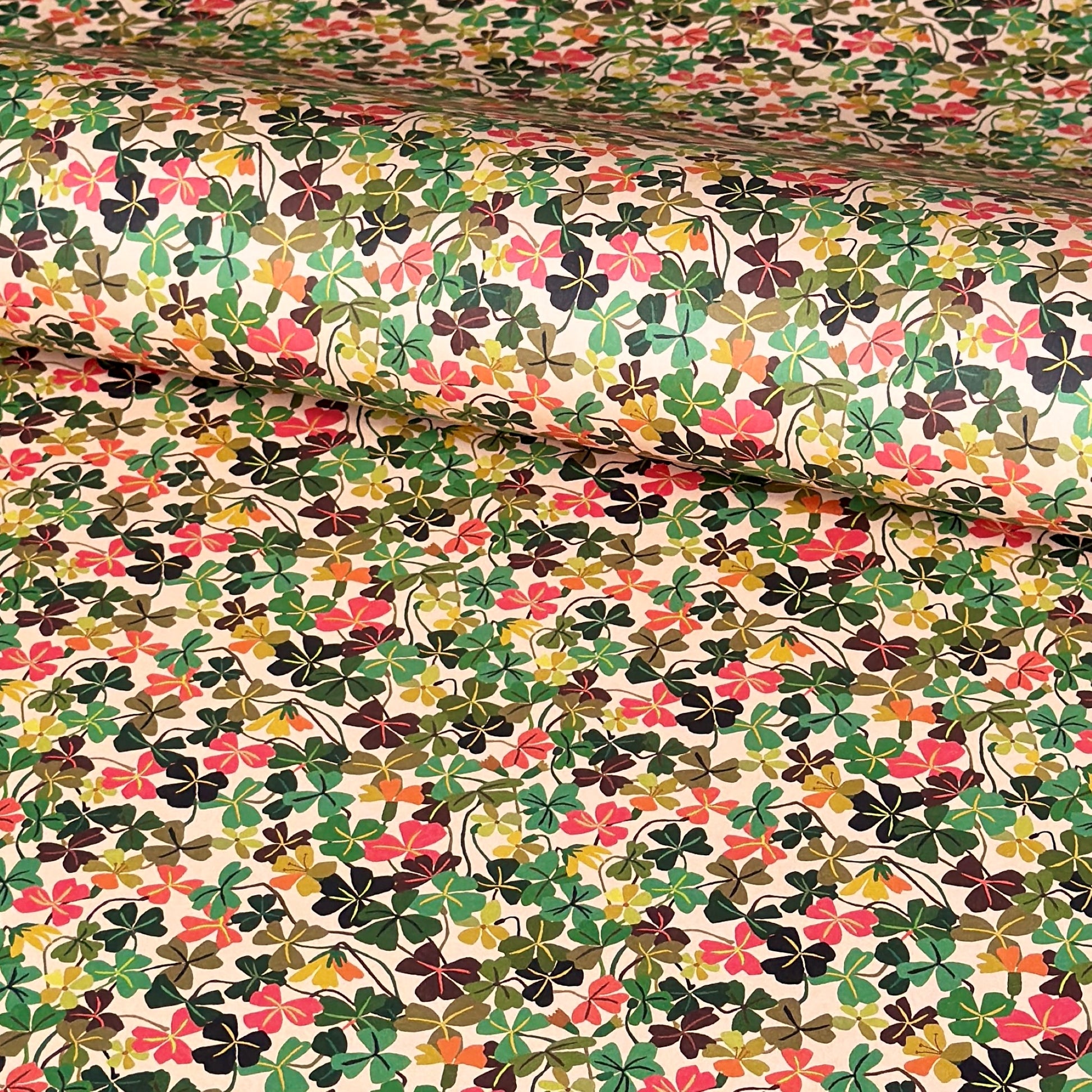 a sheet of wrapping paper with a stylised pattern of wood sorrel flowers in palette of pink, green and mustard