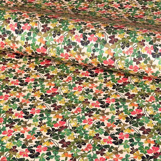 a sheet of wrapping paper with a stylised pattern of wood sorrel flowers in palette of pink, green and mustard