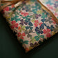 a sheet of wrapping paper with a stylised pattern of wood sorrel flowers in palette of pink, green and mustard