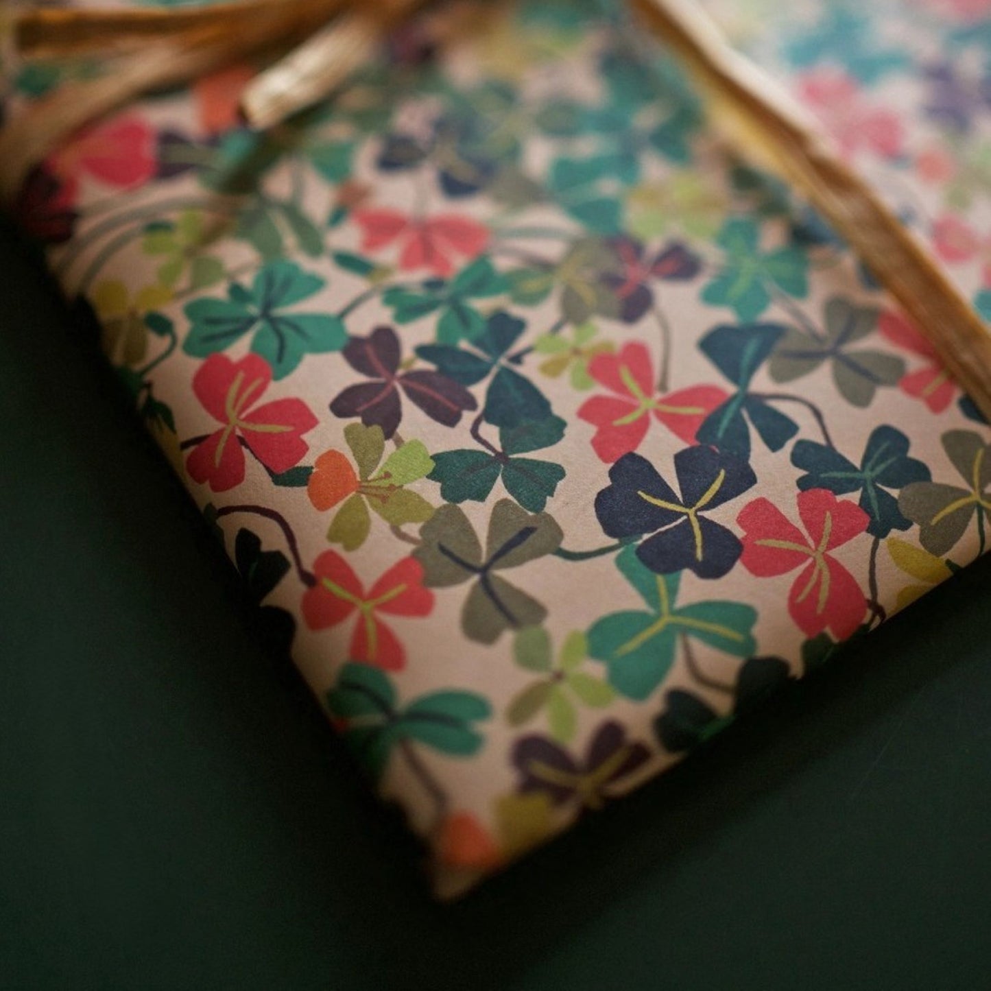 a sheet of wrapping paper with a stylised pattern of wood sorrel flowers in palette of pink, green and mustard