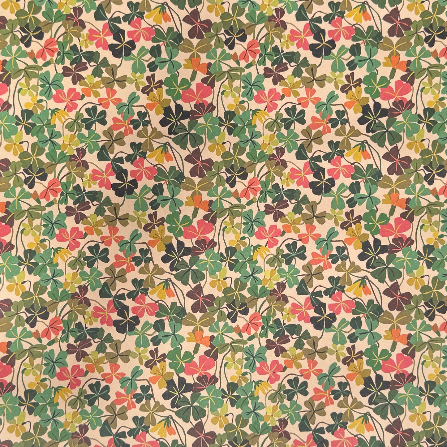 a sheet of wrapping paper with a stylised pattern of wood sorrel flowers in palette of pink, green and mustard