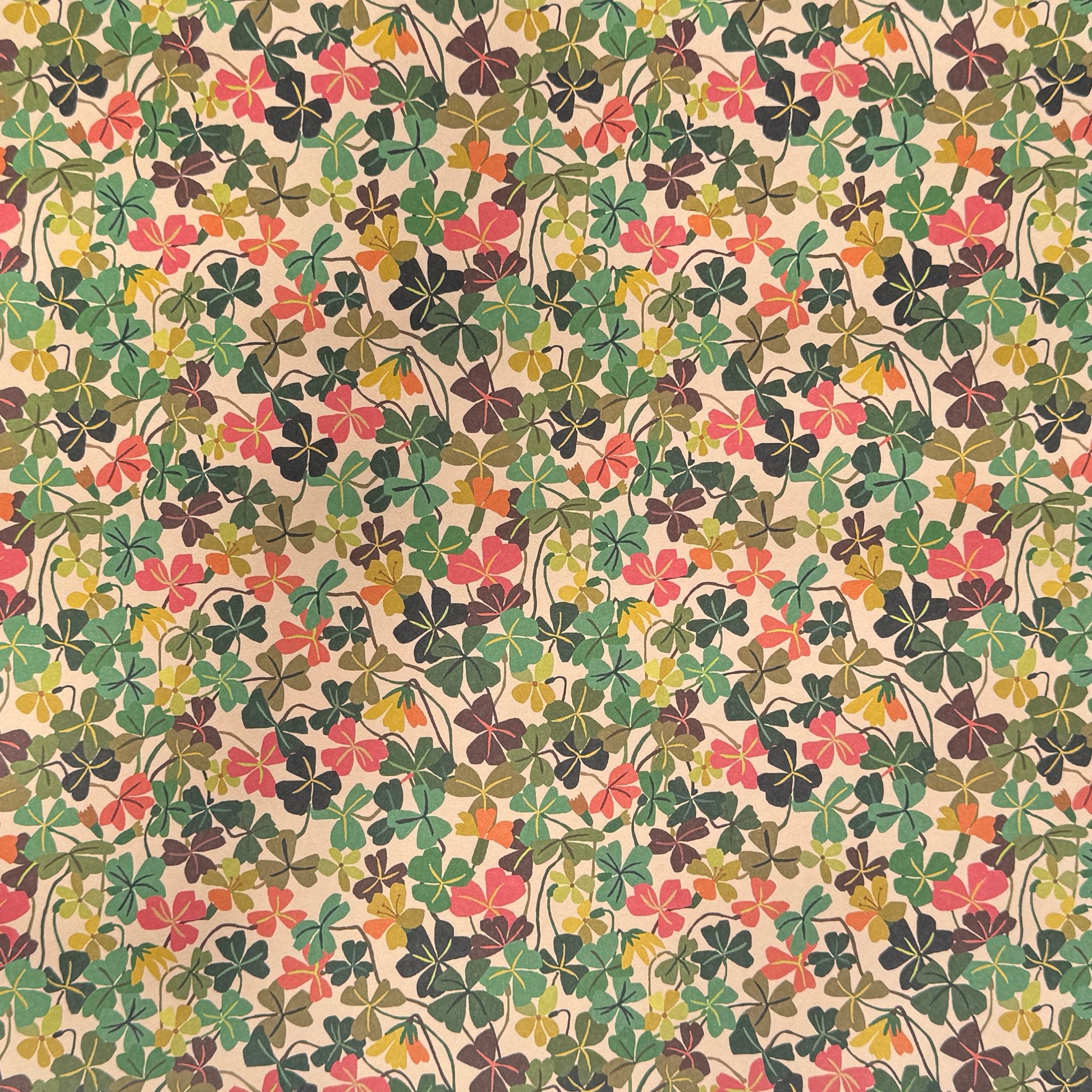 a sheet of wrapping paper with a stylised pattern of wood sorrel flowers in palette of pink, green and mustard