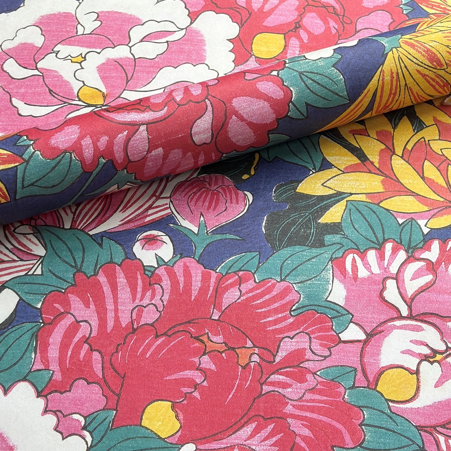 wrapping paper with a macro  design of an abundance of peonies and chrysanthemums in pink, red, yellow on a dark blue backdrop