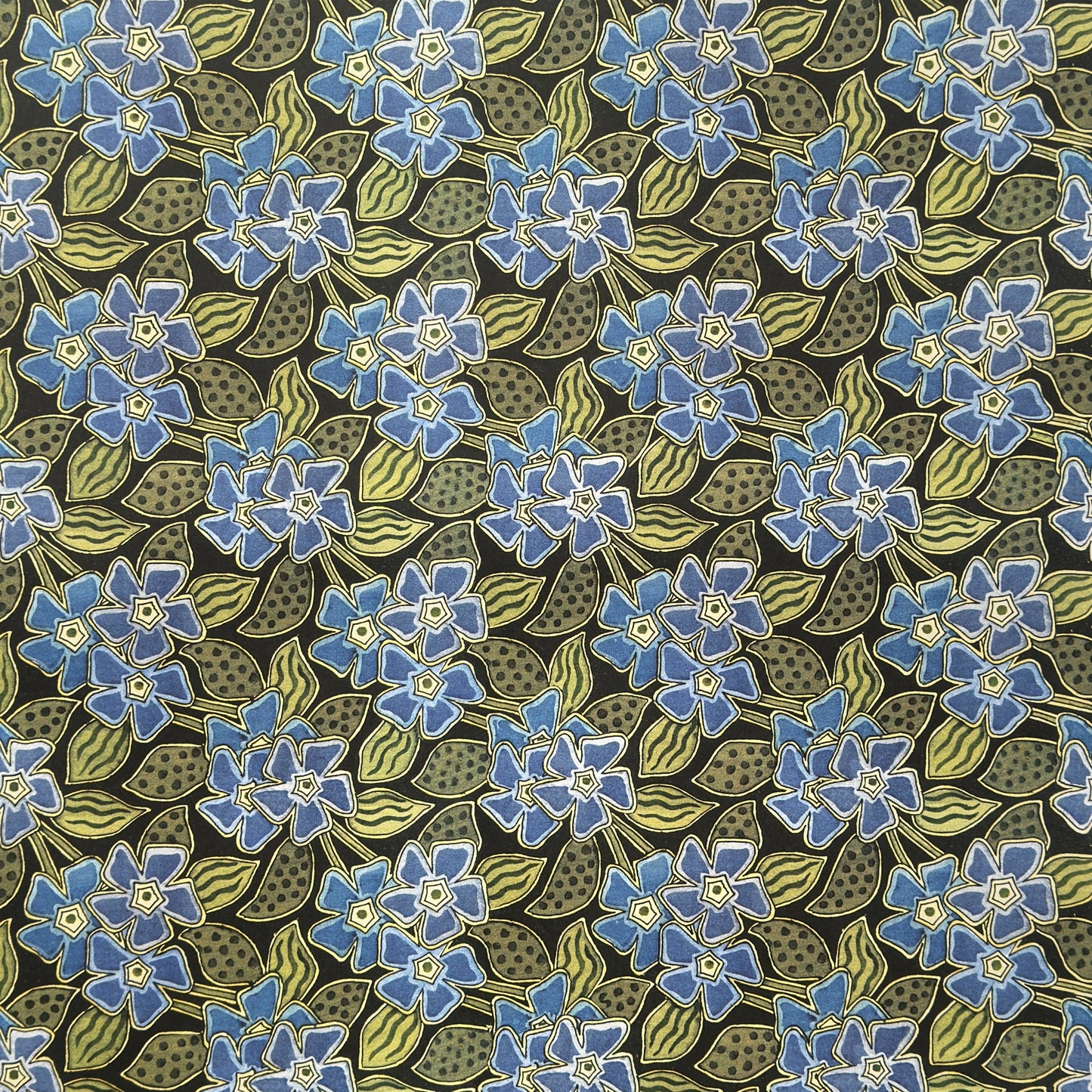 a sheet of wrapping paper with a stylised periwinkle flower design in blue and green on black