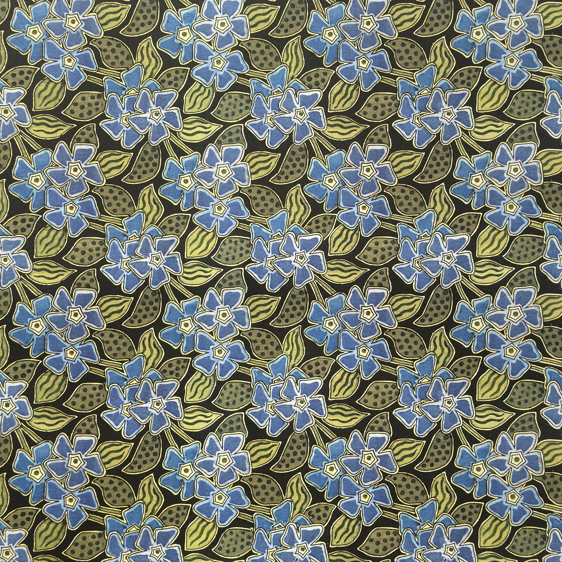 a sheet of wrapping paper with a stylised periwinkle flower design in blue and green on black
