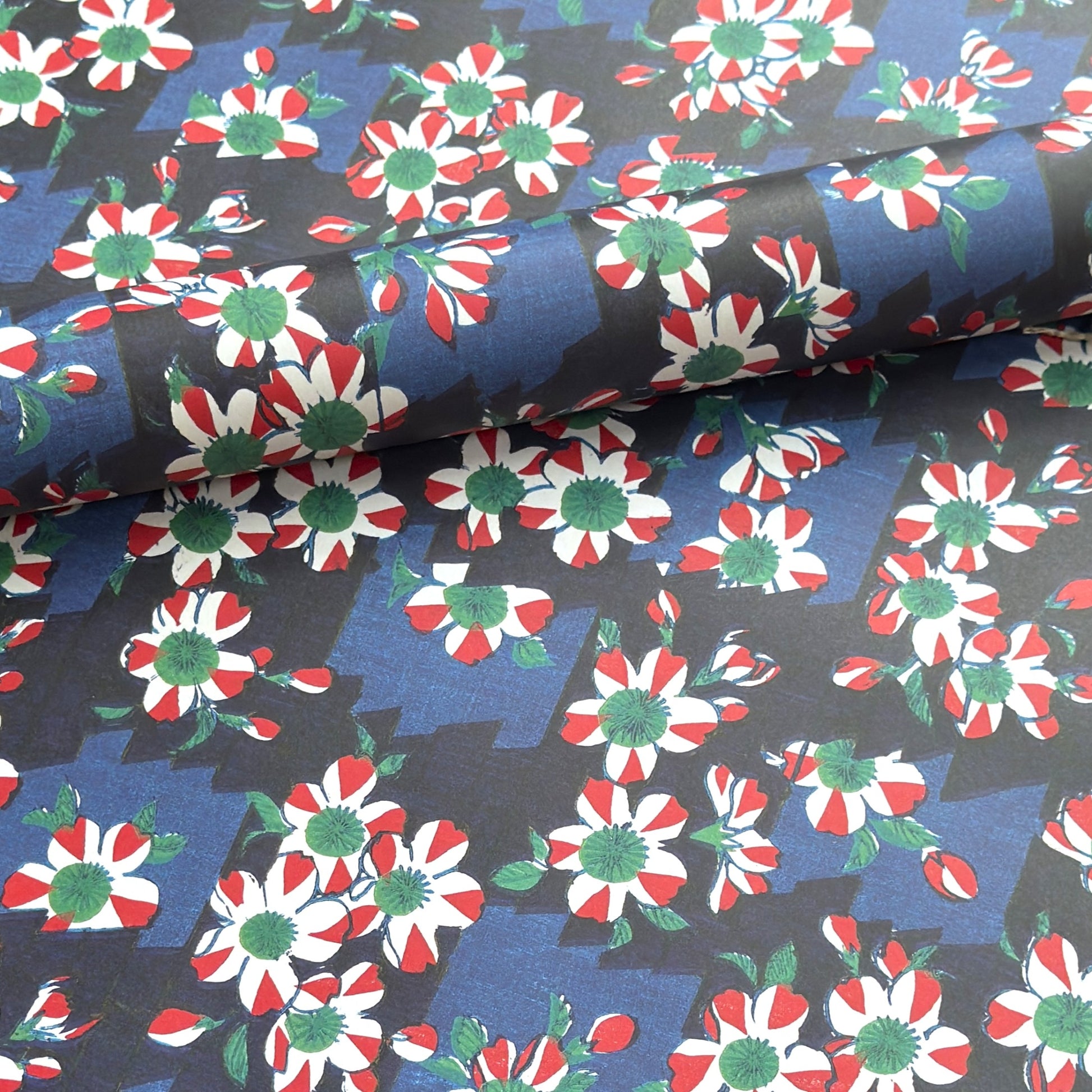 wrapping paper with a red and white flower pattern on two-toned blue background. Rolled