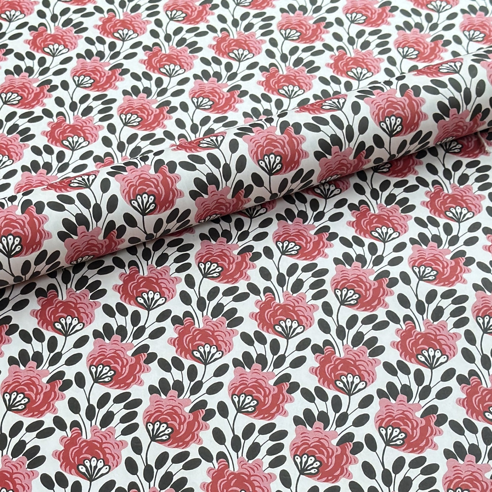wrapping paper with a repeat design of pink flowers, black seedheads on white 