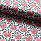 wrapping paper with a repeat design of pink flowers, black seedheads on white. Pictured rolled 