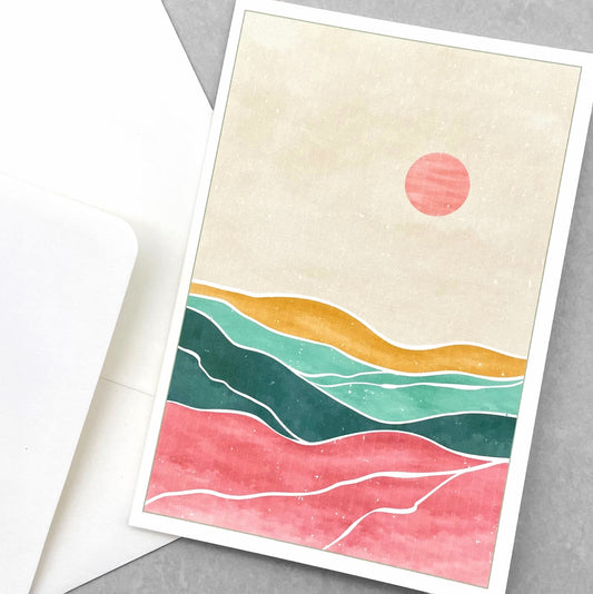 greetings card of a pink sun in the sky over a desert by com Bossa Studio