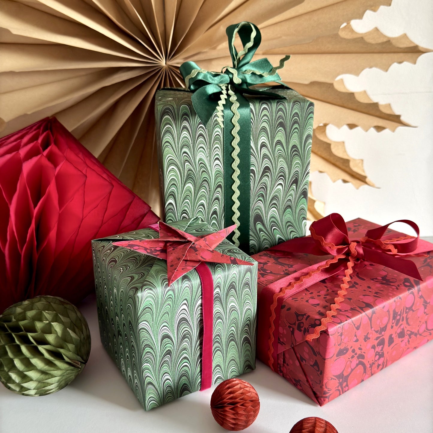 a pile of presents wrapped in printed marble papers in green swirls and deep red spotted wrapping paper