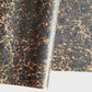 A printed marble design wrapping paper in tones of brown, blue and soft coral pink.