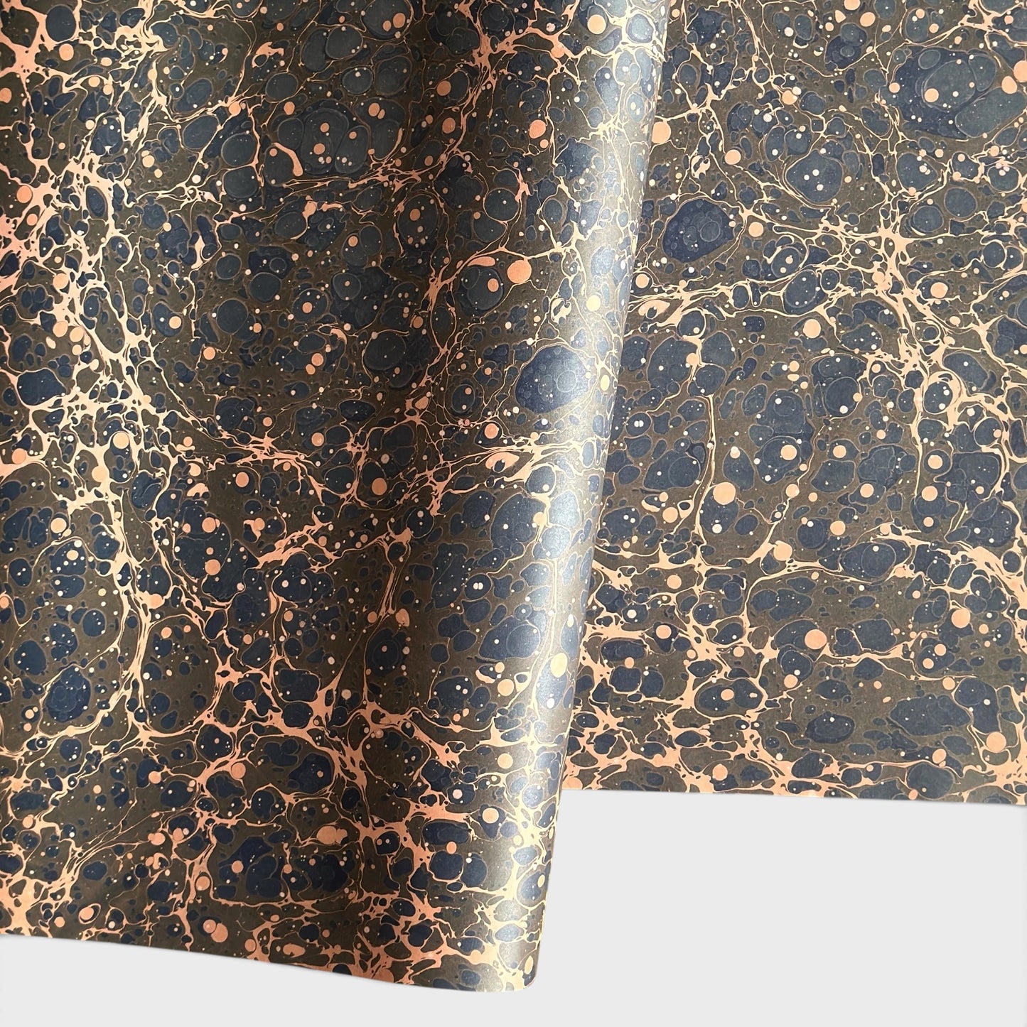 A printed marble design wrapping paper in tones of brown, blue and soft coral pink.