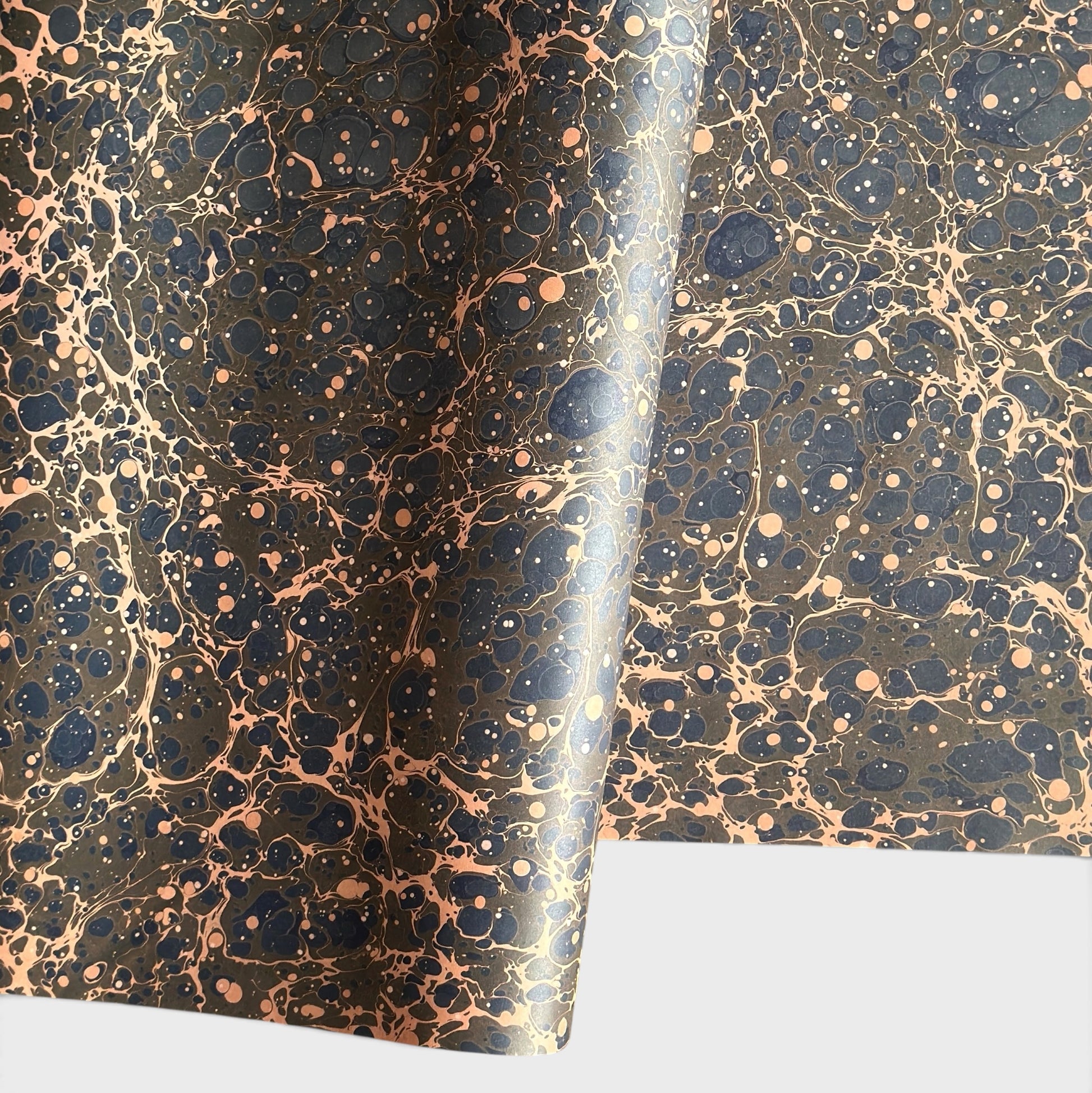 A printed marble design wrapping paper in tones of brown, blue and soft coral pink.