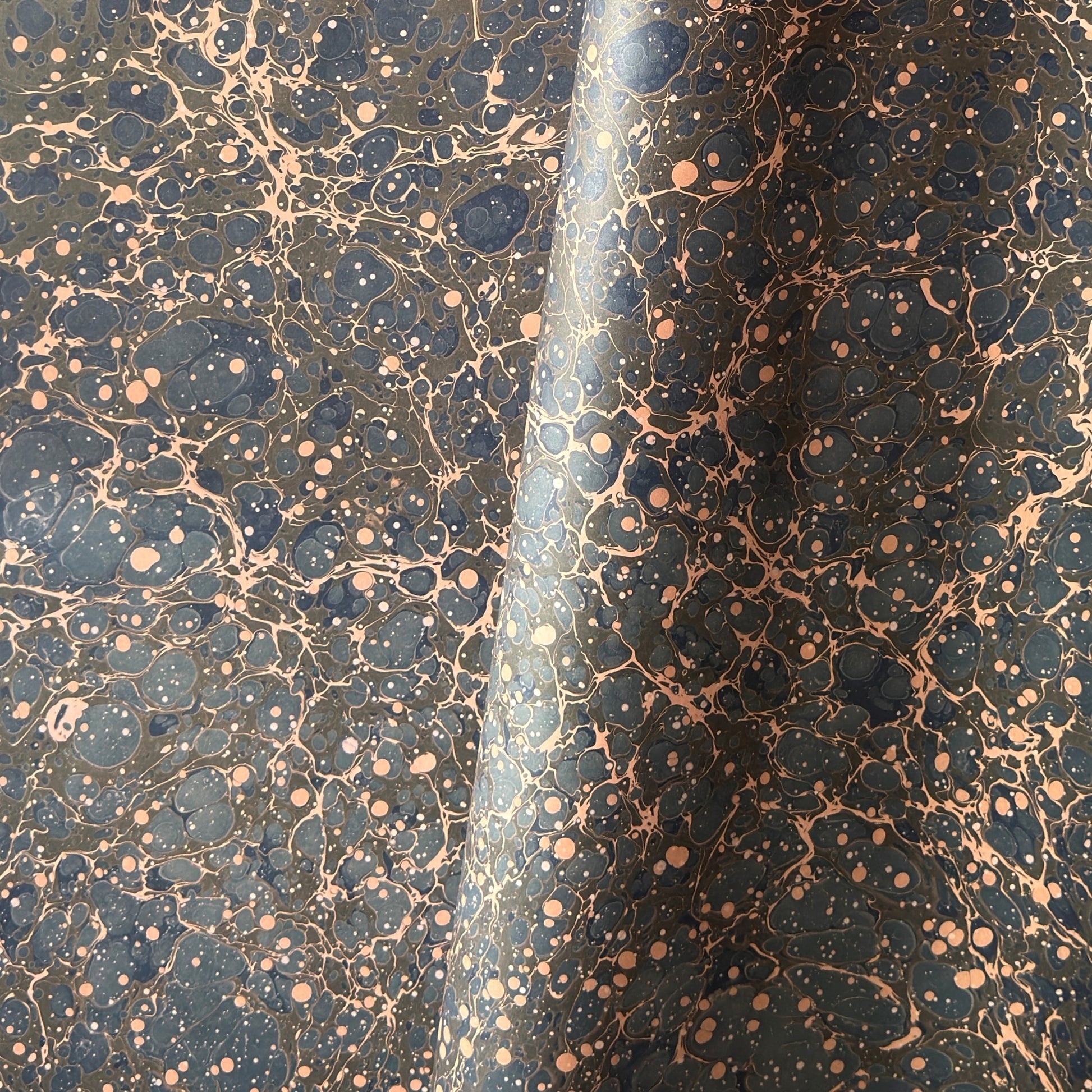 A printed marble design wrapping paper in tones of brown, blue and soft coral pink.