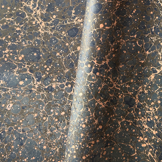 A printed marble design wrapping paper in tones of brown, blue and soft coral pink.