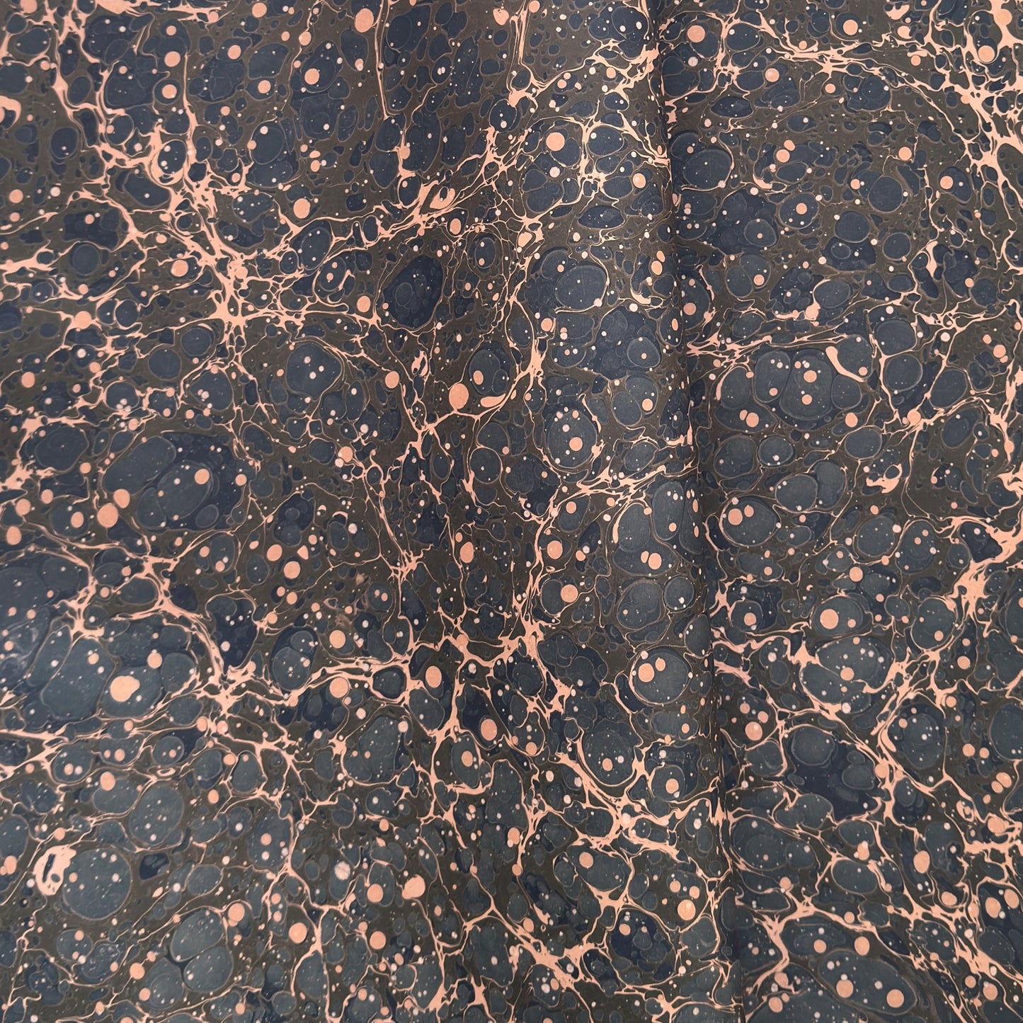 A printed marble design wrapping paper in tones of brown, blue and soft coral pink.