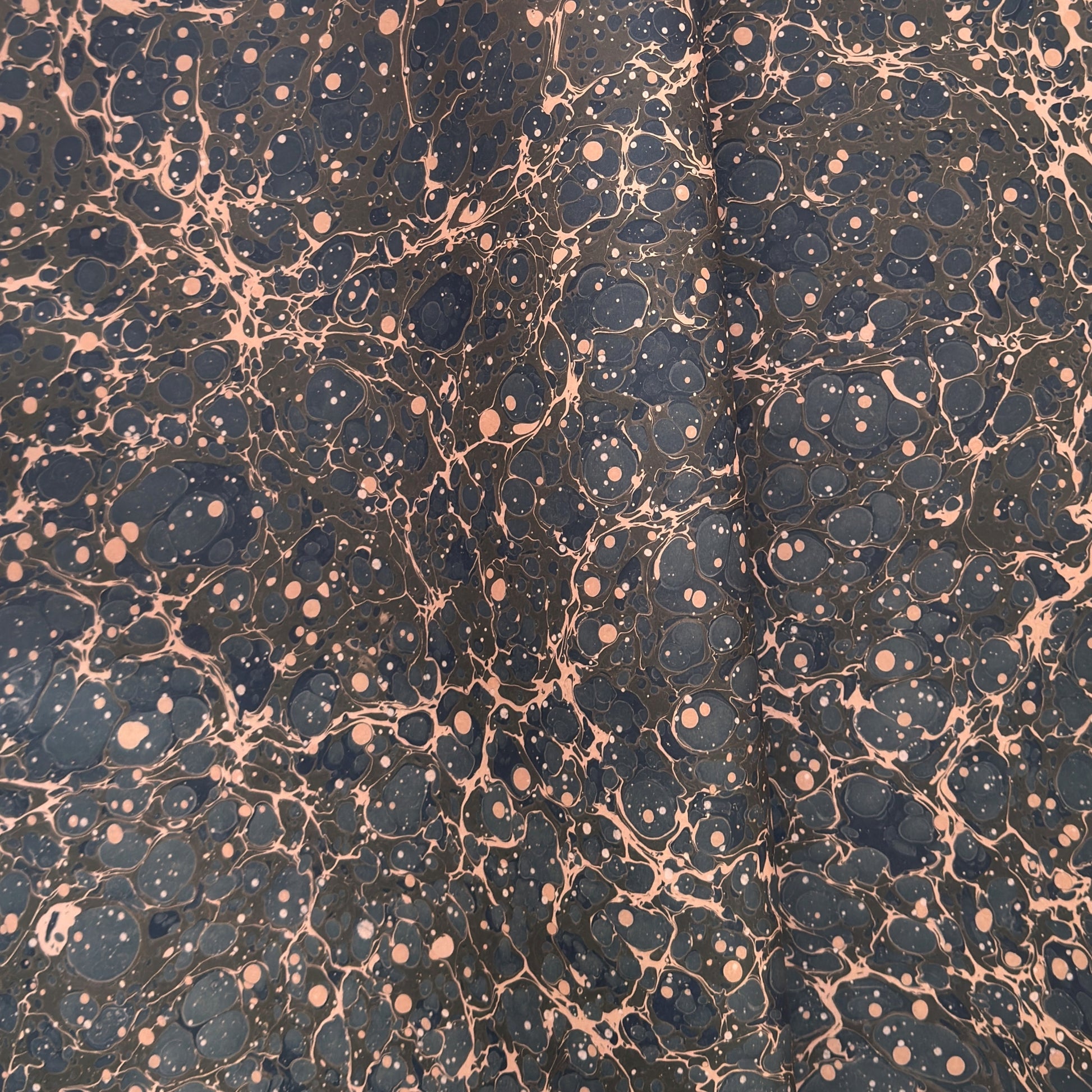 A printed marble design wrapping paper in tones of brown, blue and soft coral pink.