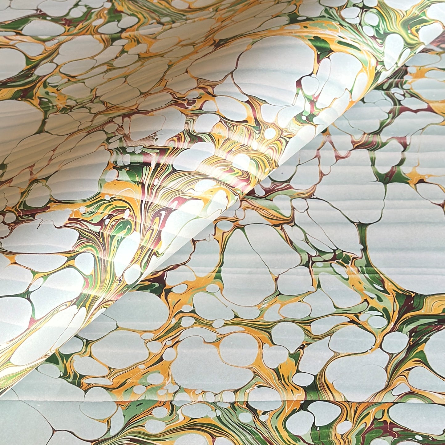 Printed marbled gift wrapping paper by Compton Marbling with a stone marbling pattern in soft grey, green and mustard.
