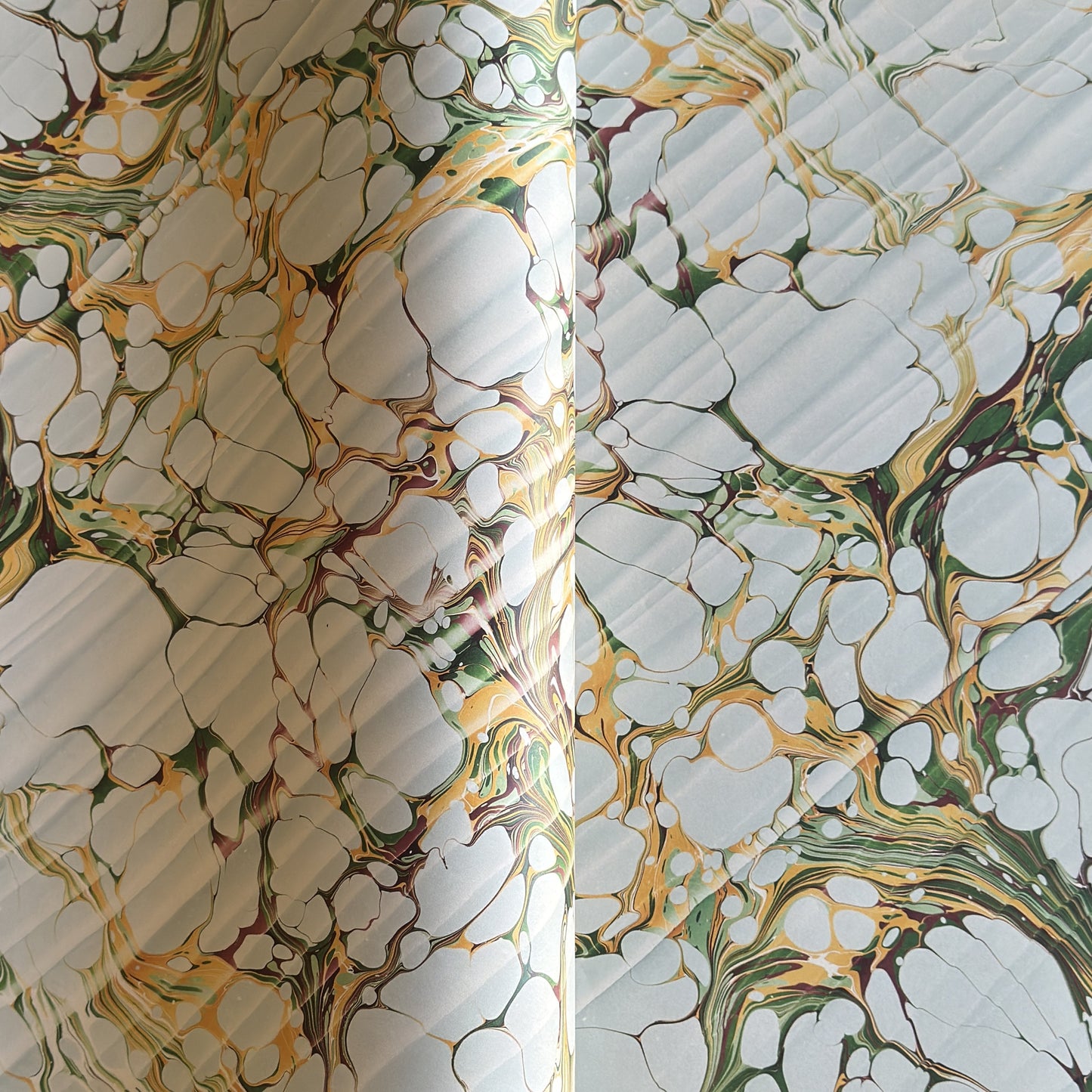 Printed marbled gift wrapping paper by Compton Marbling with a stone marbling pattern in soft grey, green and mustard.