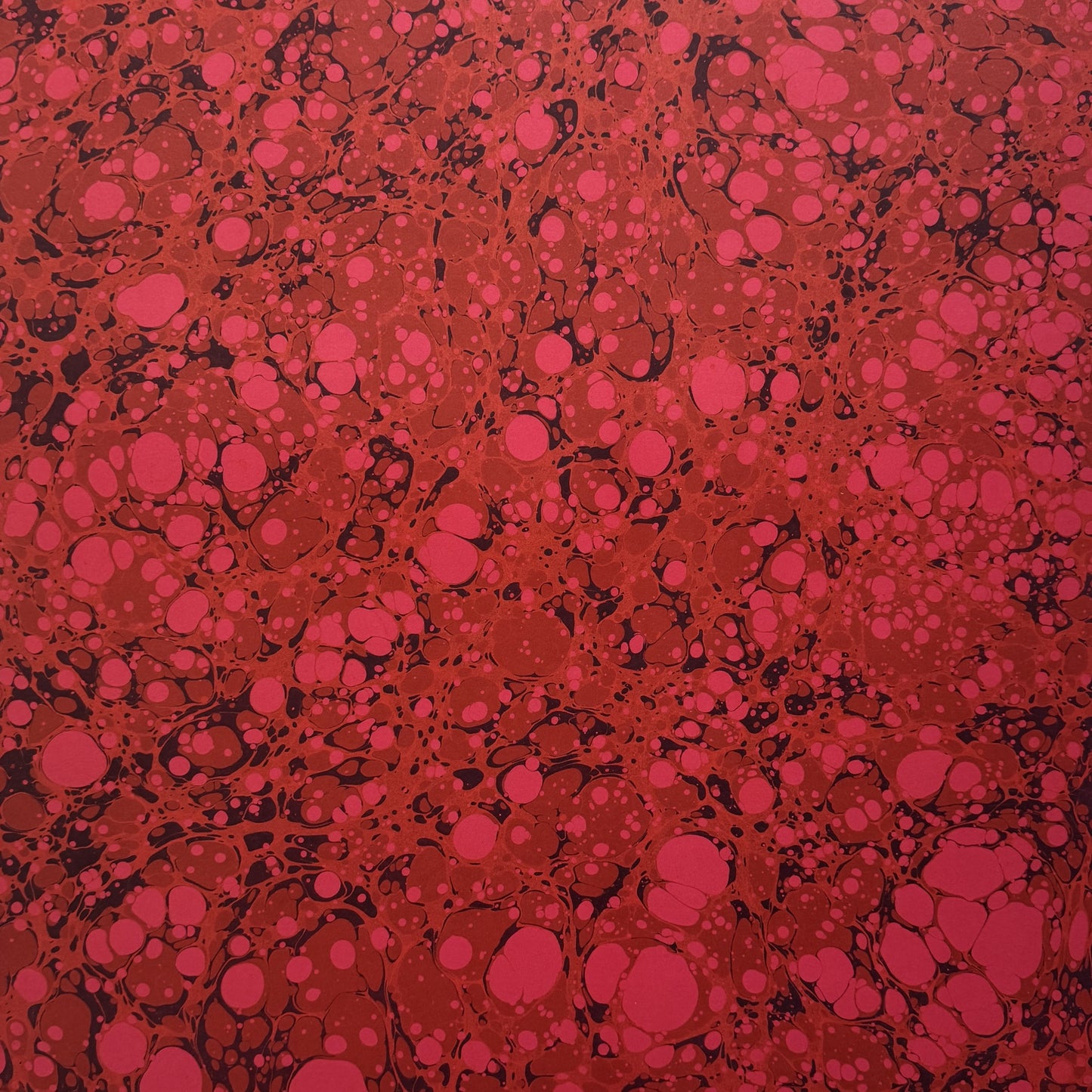 printed wrapping paper with a marbled stone pattern in deep reds and pinks by Compton Marbling