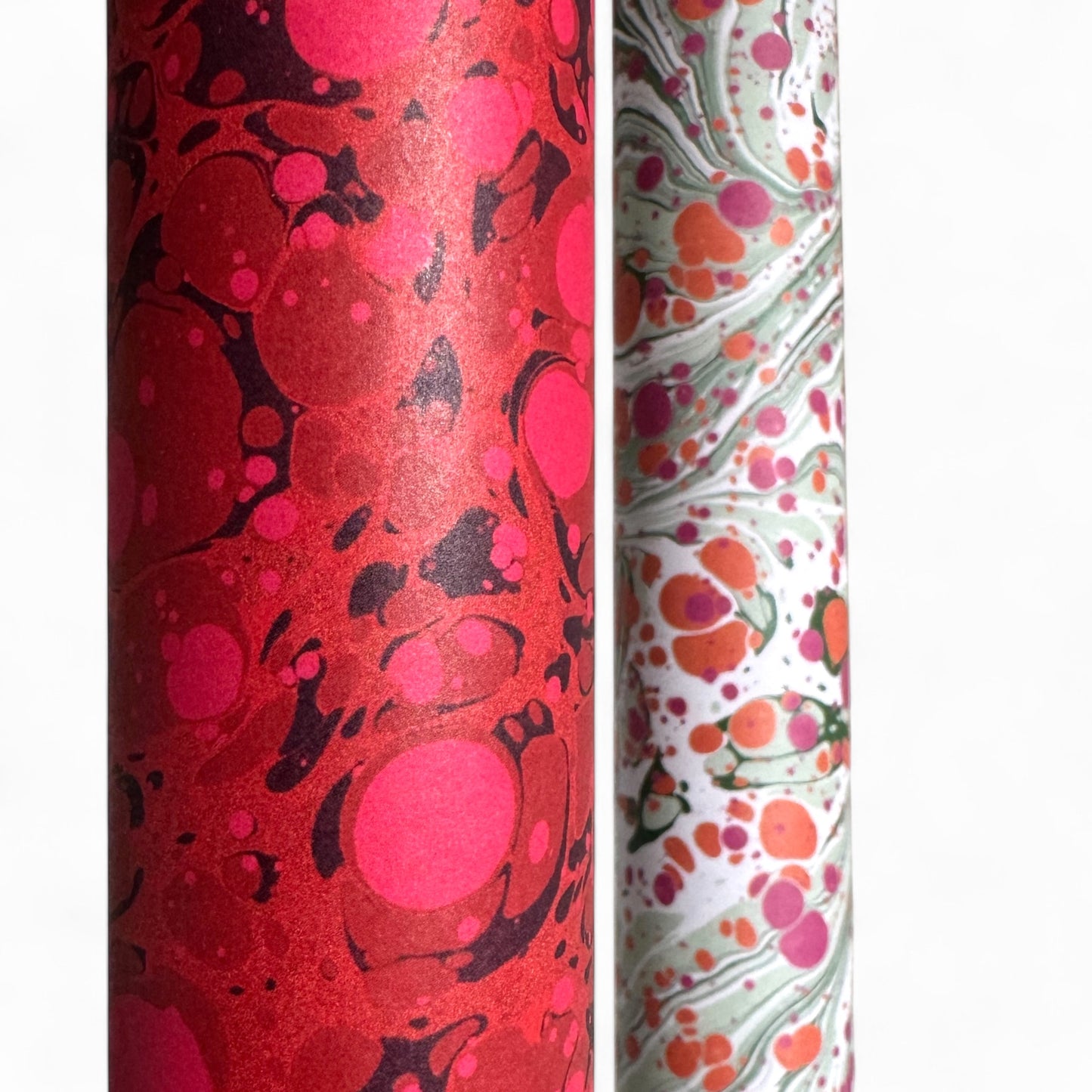 printed wrapping paper with a marbled stone pattern in deep reds and pinks by Compton Marbling - close up of a rolled sheet of gift wrap