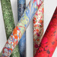 printed marble wrapping paper with a swirl design in blue, orange, green and pink. By Compton Marbling. Pictured with other rolls of marbled paper