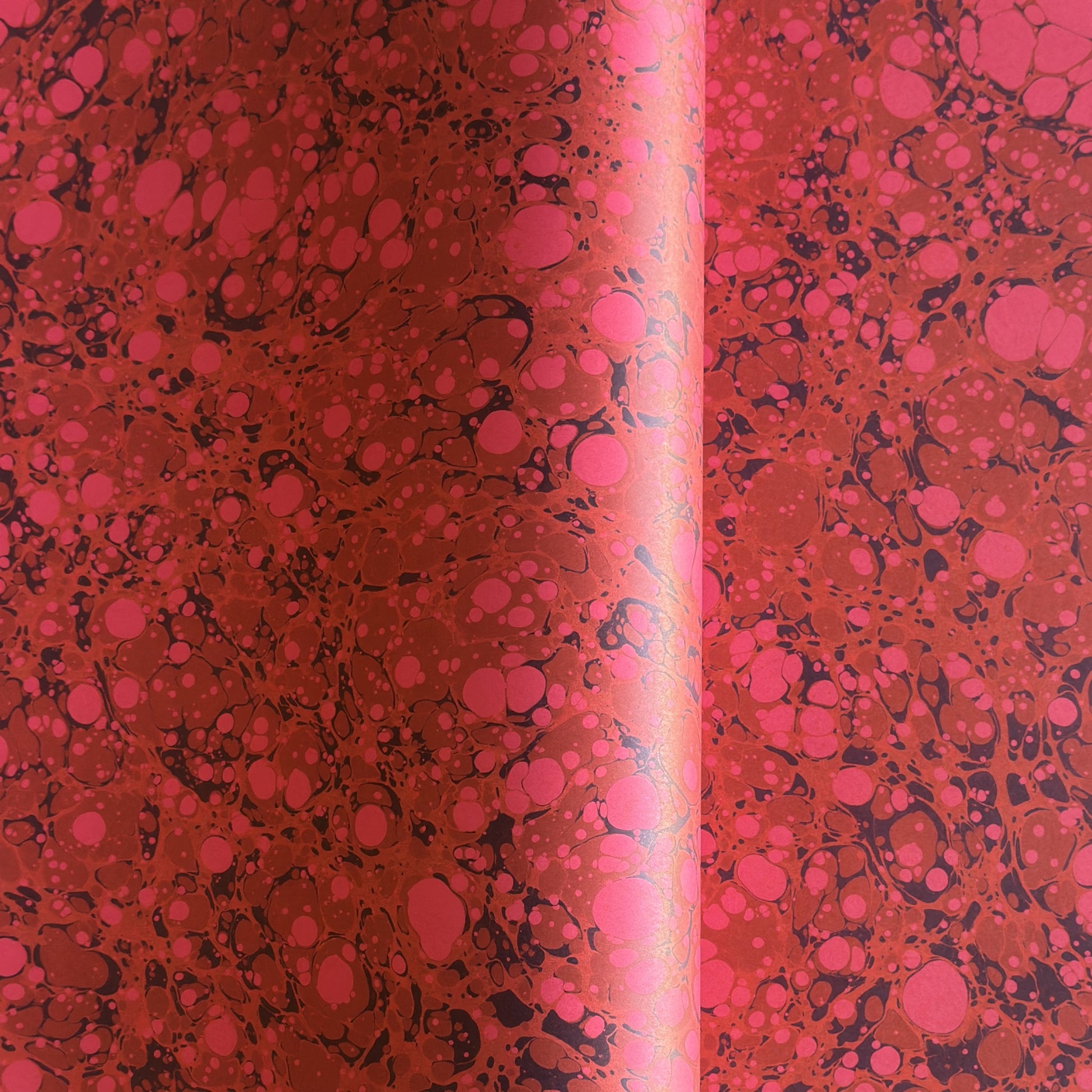 printed wrapping paper with a marbled stone pattern in deep reds and pinks by Compton Marbling