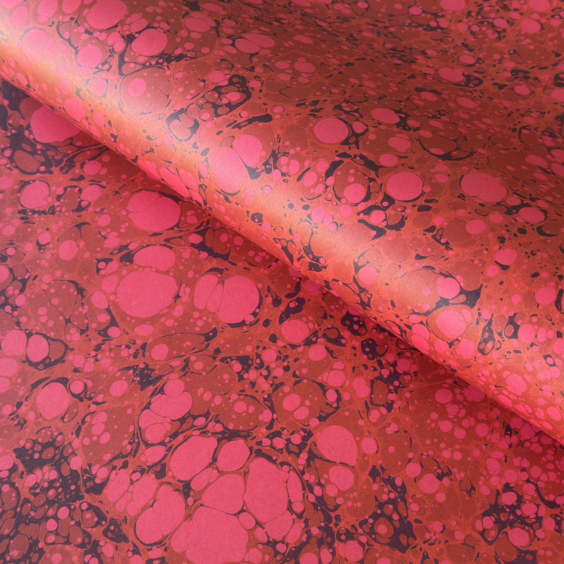printed wrapping paper with a marbled stone pattern in deep reds and pinks by Compton Marbling
