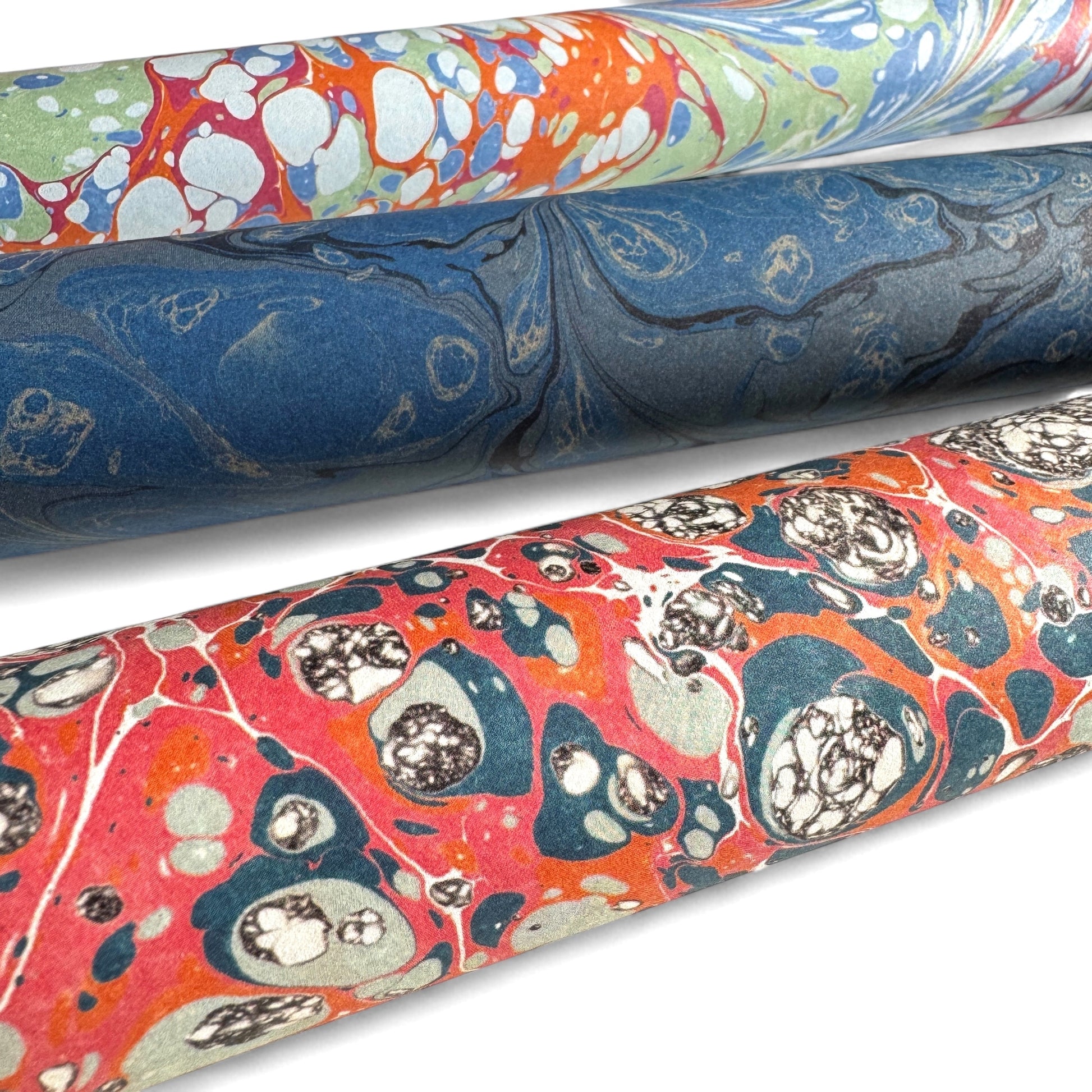 a printed marbled design wrapping paper in blue, orange and pink, by Compton Marbling. Close up