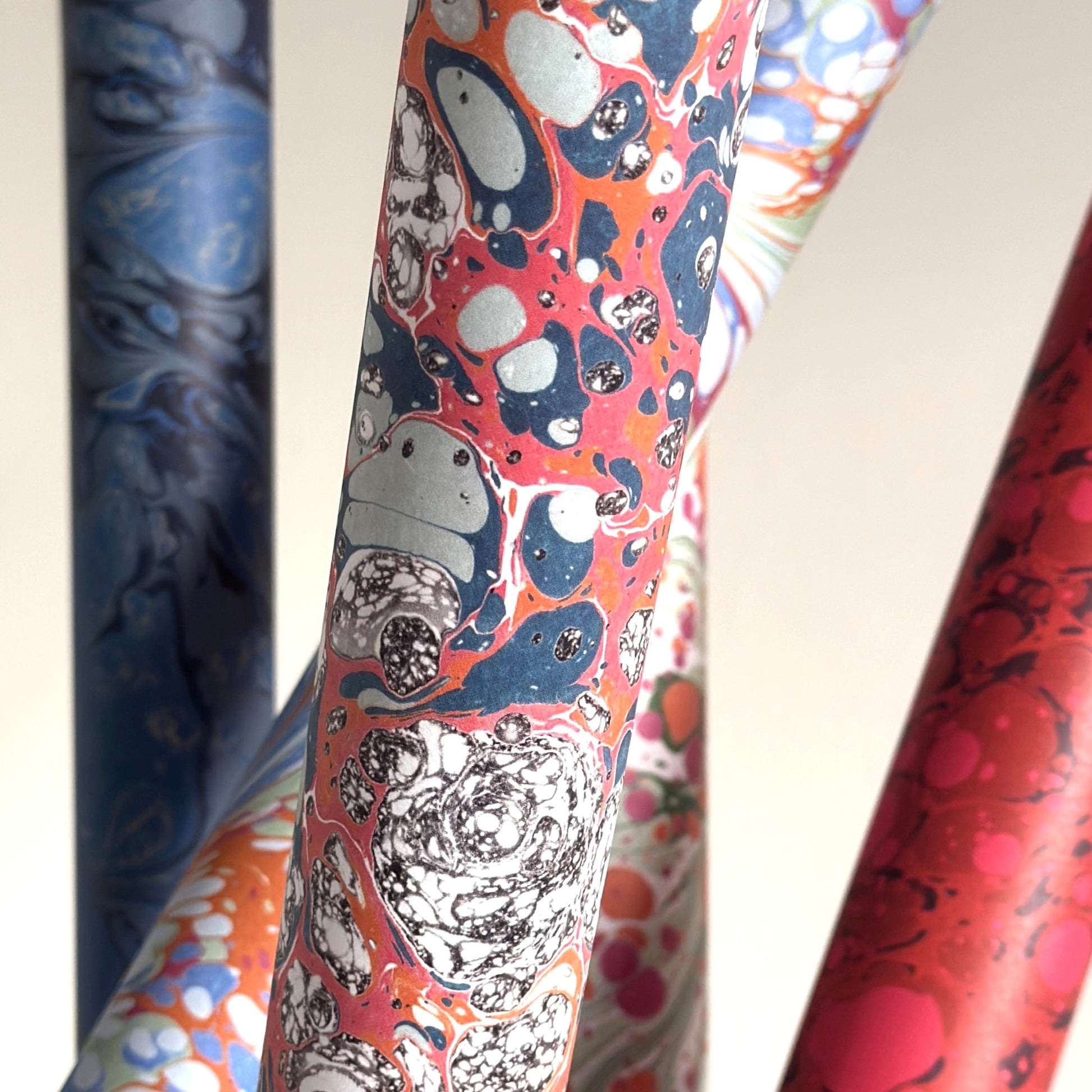 a printed marbled design wrapping paper in blue, orange and pink, by Compton Marbling