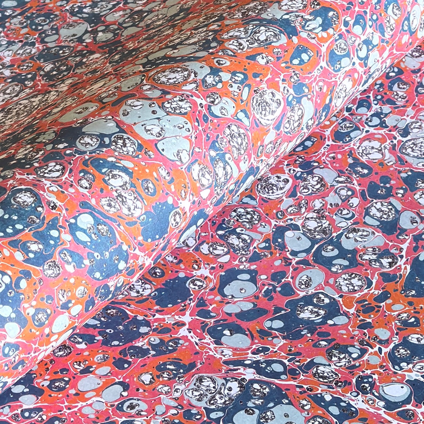 a printed marbled design wrapping paper in blue, orange and pink, by Compton Marbling