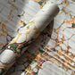 Printed marbled gift wrapping paper by Compton Marbling with a stone marbling pattern in soft grey, green and mustard.