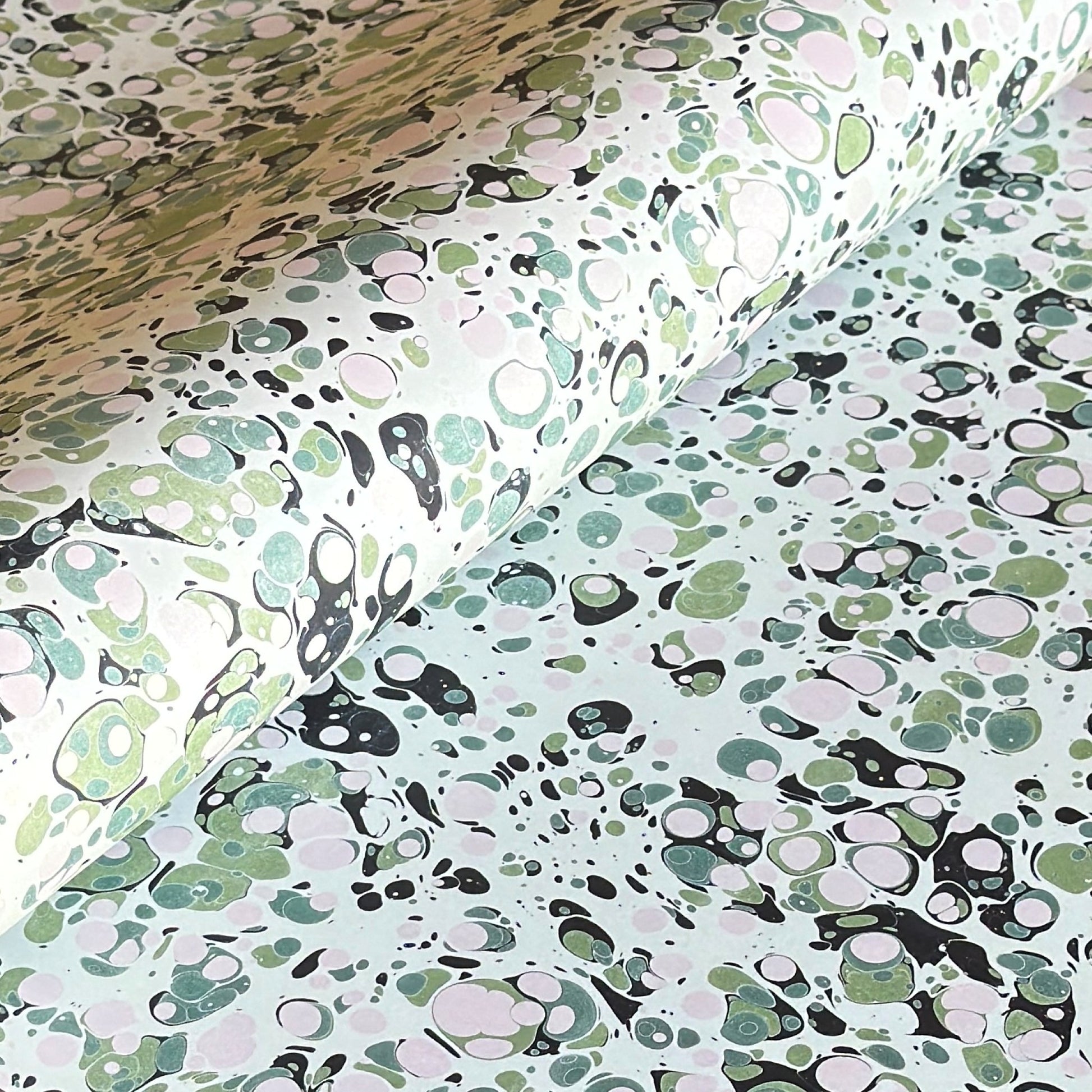 marbled printed wrapping paper with spot design in moss green, pale pink on a soft green.