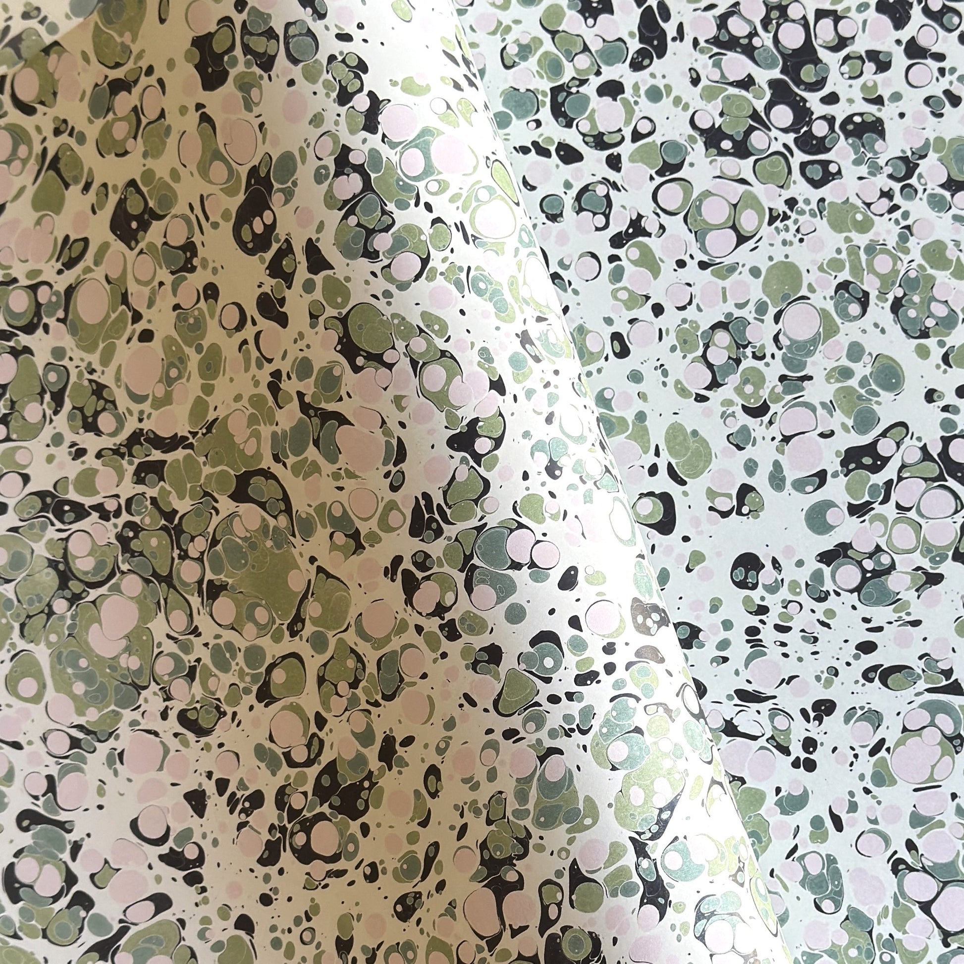 marbled printed wrapping paper with spot design in moss green, pale pink on a soft green.