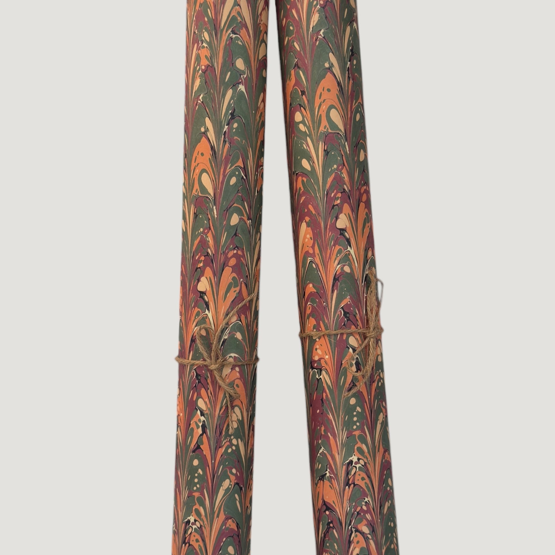 Printed marbled gift wrapping paper by Compton Marbling with a ripple marbled pattern in soft green, burgundy, cream and amber. Pictured rolled