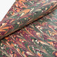 Printed marbled gift wrapping paper by Compton Marbling with a ripple marbled pattern in soft green, burgundy, cream and amber.  Close up