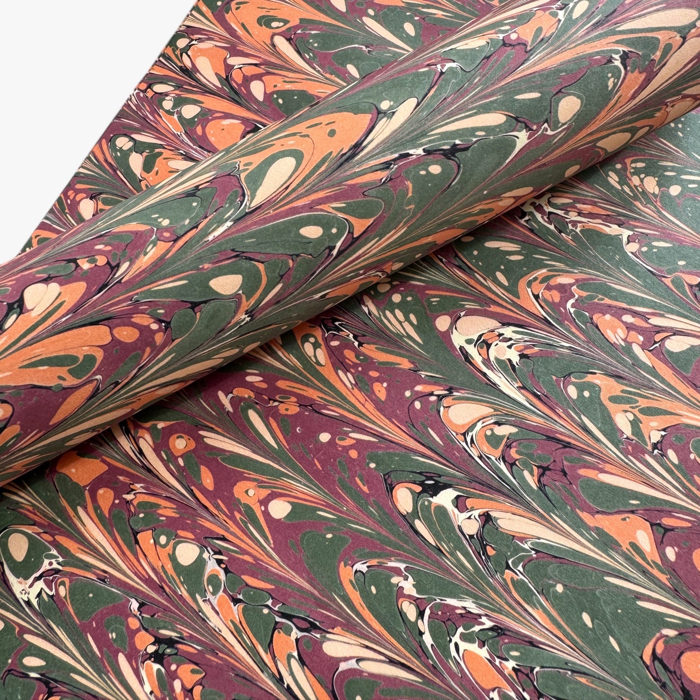 Printed marbled gift wrapping paper by Compton Marbling with a ripple marbled pattern in soft green, burgundy, cream and amber.  Close up