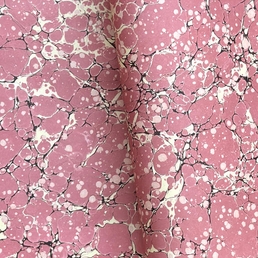 a sheet of wrapping paper with a pink marbled pattern with white and black veined design