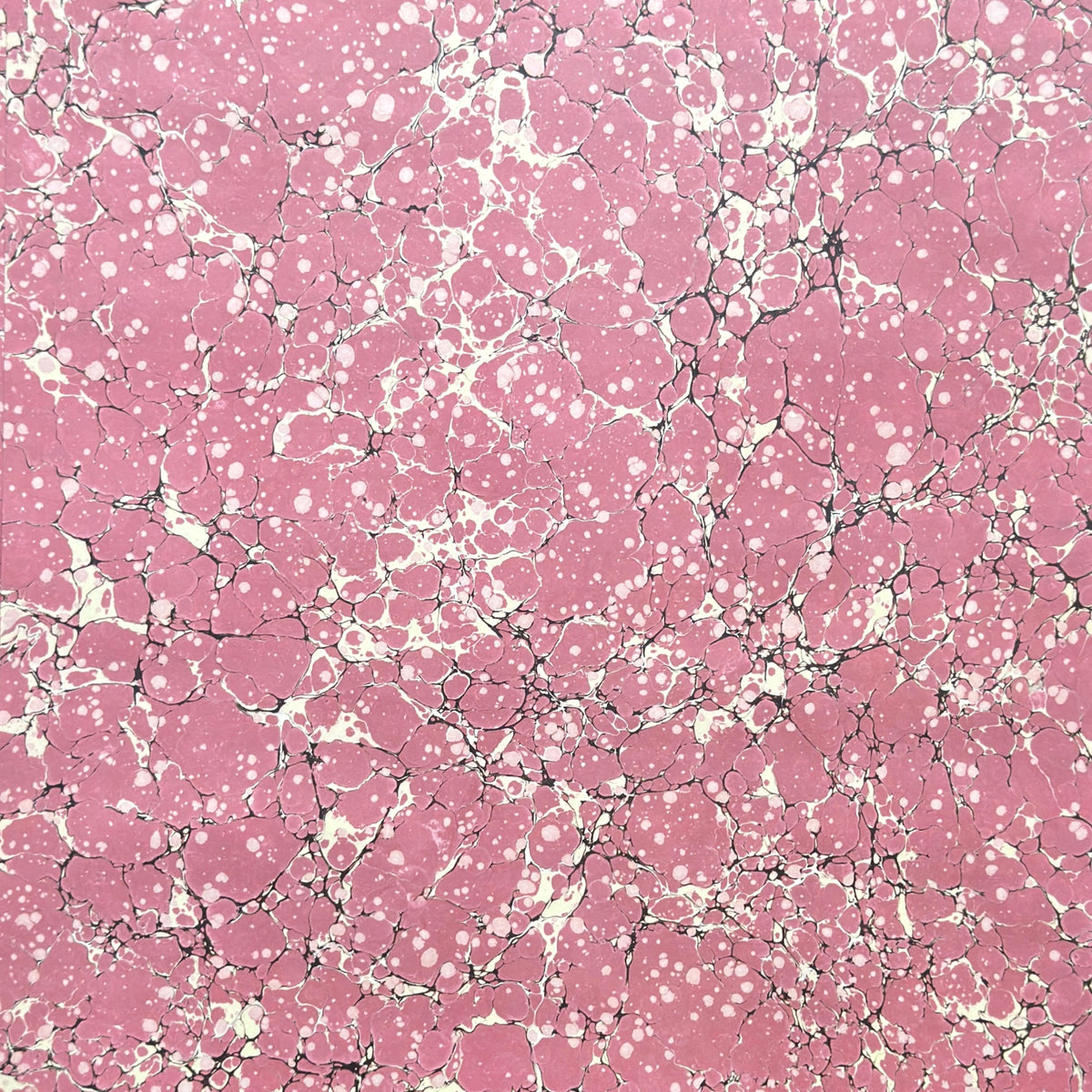 a sheet of wrapping paper with a pink marbled pattern with white and black veined design