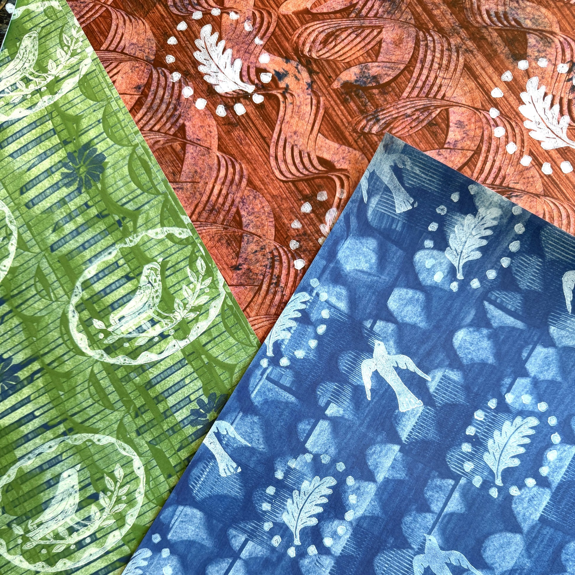 a sheet of wrapping paper from the Danby Press with a  backdrop of green paste paper design and circular stamped white bird motifs. Pictured with other painterly designs