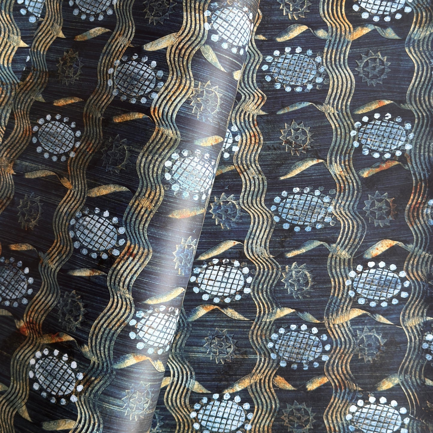  a sheet of wrapping paper with a relief printed star and flower in white on a inky blue paste paper backdrop